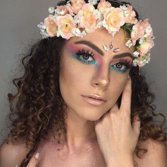mulher com coroa de flores e maquiagem rosa e azul nos olhos para o carnaval