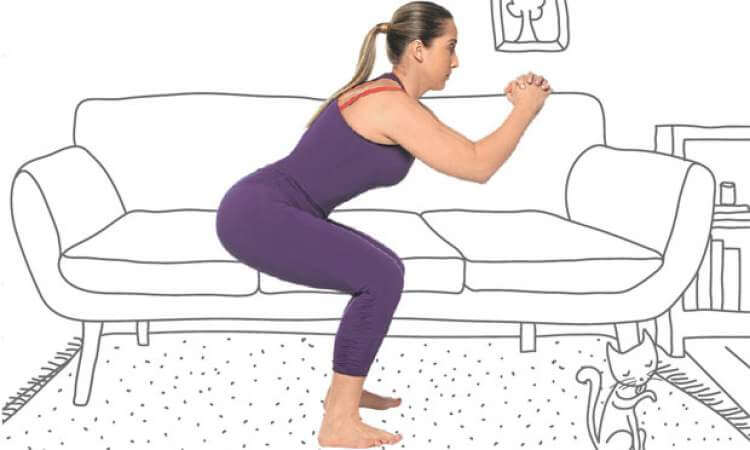 Mulher fazendo exercícios de agachamento na sala de casa