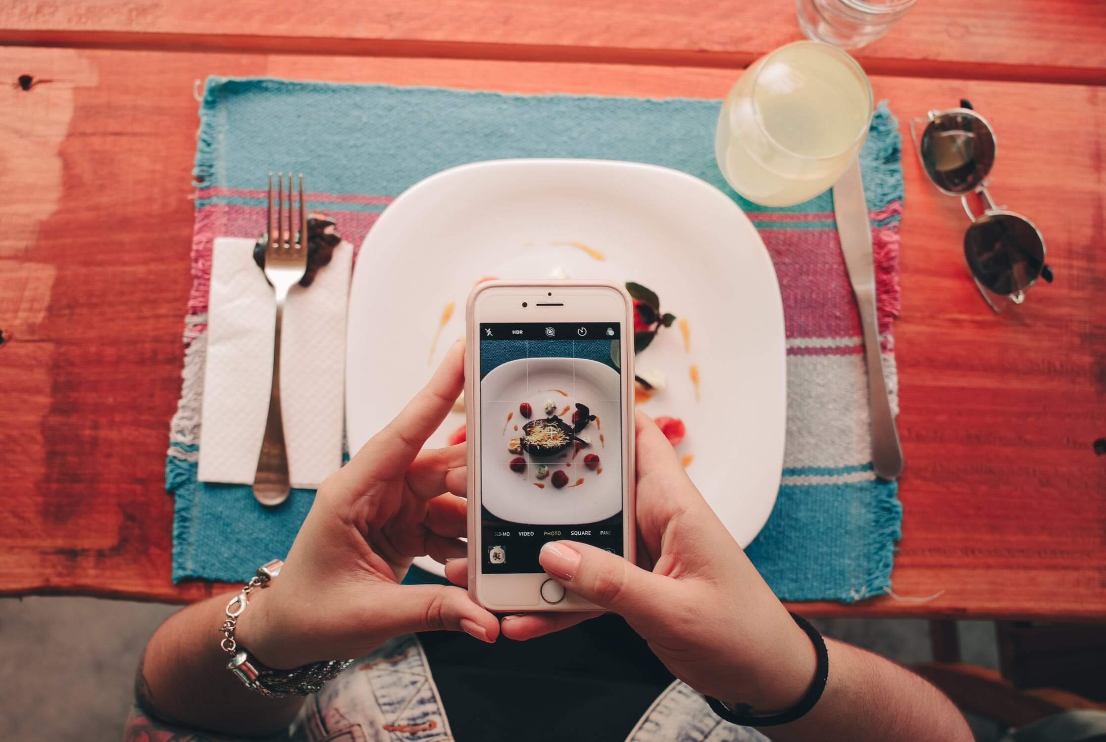 mulher mexendo em um aplicativo de celular com as mãos em cima de um prato