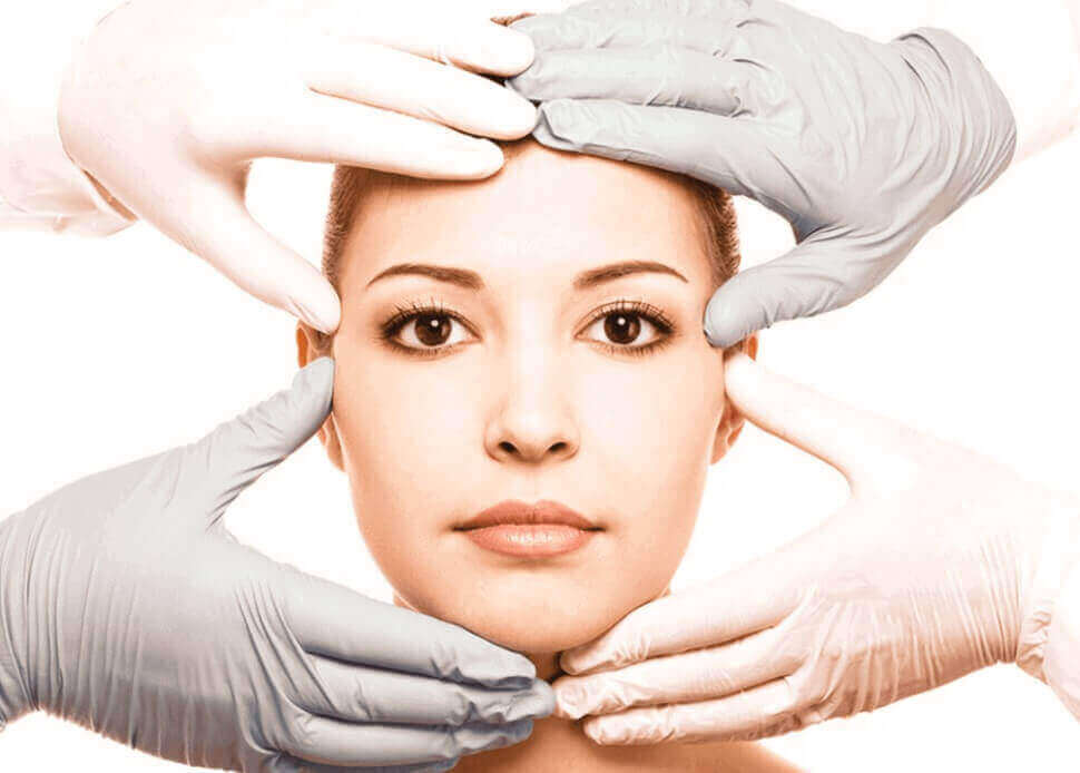 mãos com luvas cirurgicas no rosto de uma mulher antes da Cirurgia Plástica