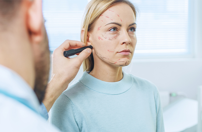 mulher sentada em consultório enquanto médico avalia seu rosto para procedimentos estéticos