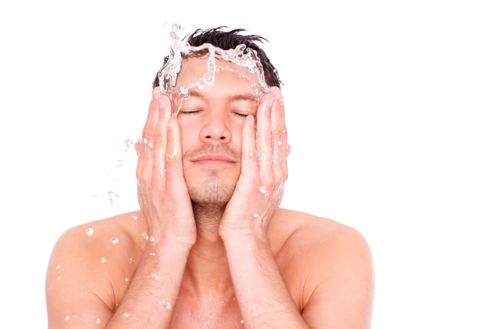 Homem higienizando o rosto para iniciar uma limpeza de pele masculina