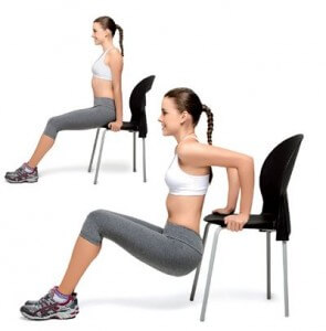 Mulher se apoiando em uma cadeira para fazer exercício de fortalecer as coxas.