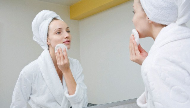 Mulher em frente ao espelho fazendo Limpeza da pele