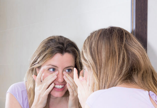 Mulher olhando seu rosto no espelho