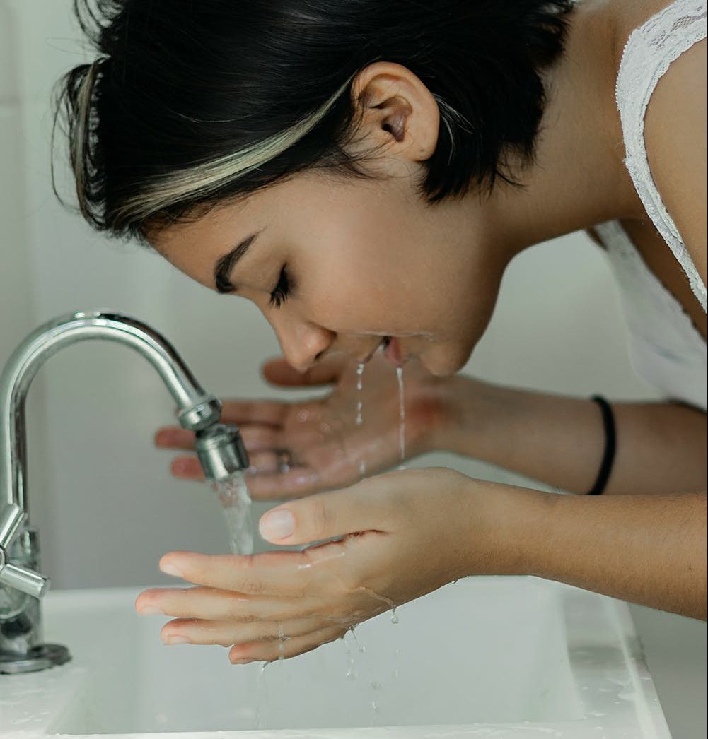 Mulher jovem, lavando o rosto em um lavabo branco