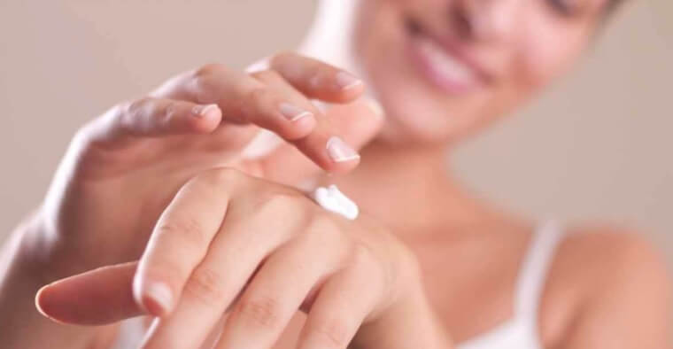 Mulher aplicando cremes para prevenir envelhecimento da pele das mãos